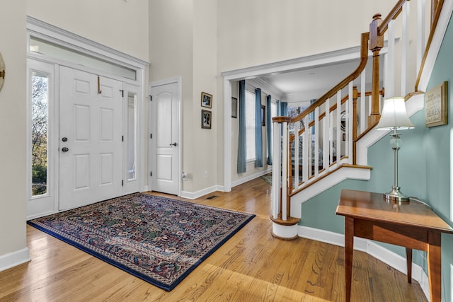 foyer featuring wood-type flooring and crown molding