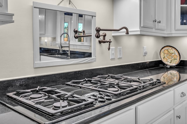 room details featuring white cabinets, stainless steel gas stovetop, and sink