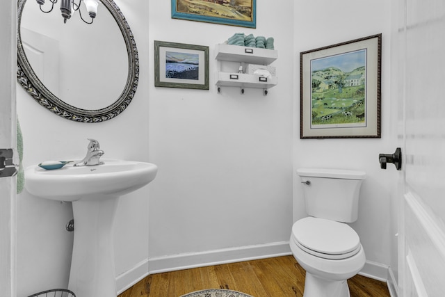 bathroom with toilet, wood-type flooring, and sink