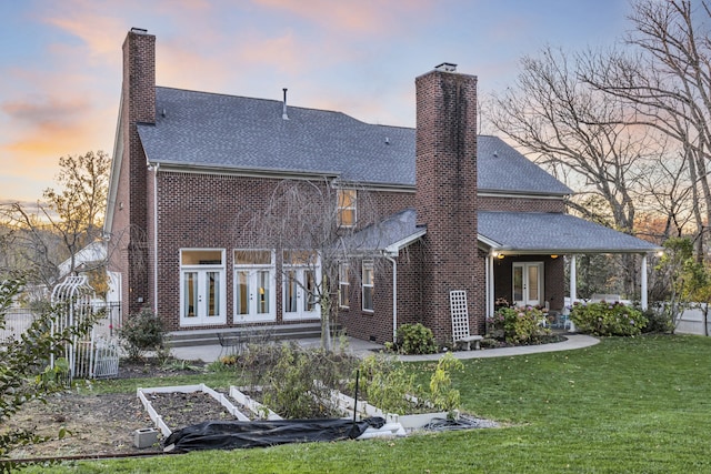 back house at dusk with a yard and french doors