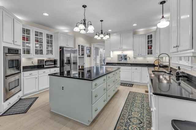 kitchen with white cabinets, sink, stainless steel appliances, and hanging light fixtures