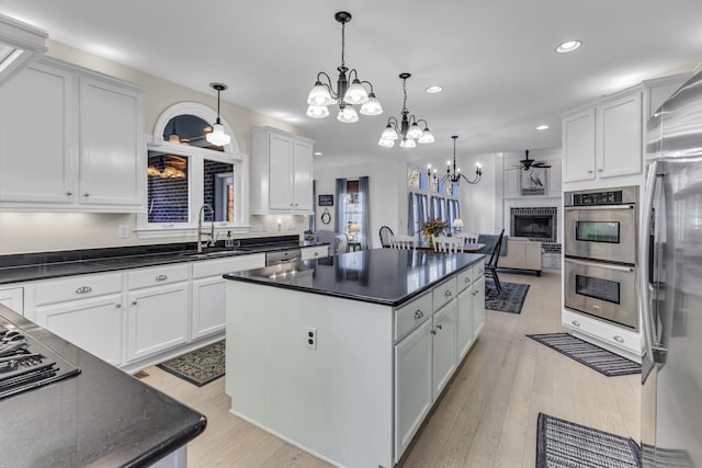 kitchen with sink, a center island, stainless steel appliances, hanging light fixtures, and white cabinets