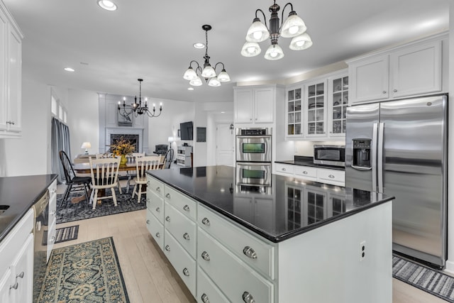 kitchen with white cabinets, a center island, stainless steel appliances, and hanging light fixtures