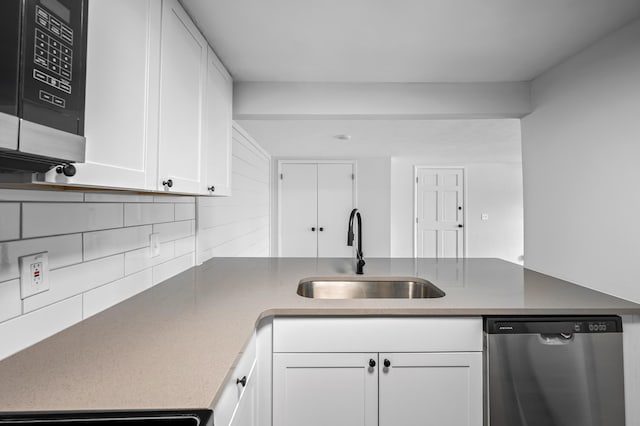 kitchen featuring sink, appliances with stainless steel finishes, white cabinets, decorative backsplash, and kitchen peninsula