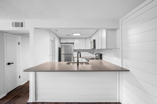 kitchen with white cabinetry, stainless steel appliances, kitchen peninsula, and sink