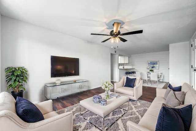 living room featuring dark wood-type flooring and ceiling fan