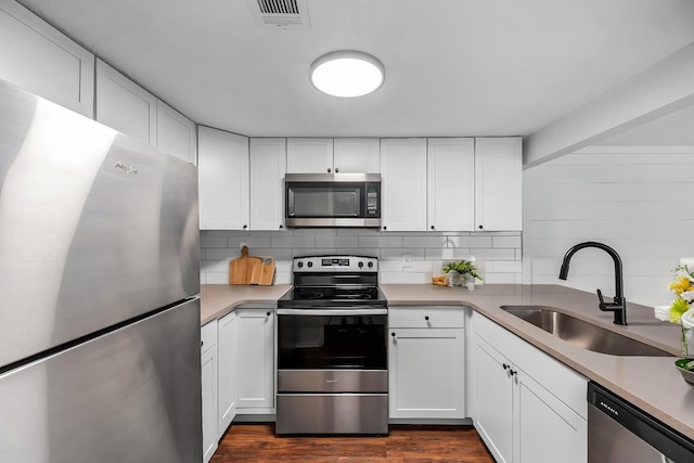 kitchen featuring sink, appliances with stainless steel finishes, dark hardwood / wood-style floors, tasteful backsplash, and white cabinets