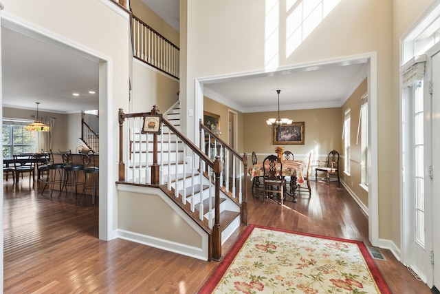 entryway with dark hardwood / wood-style flooring, an inviting chandelier, and crown molding