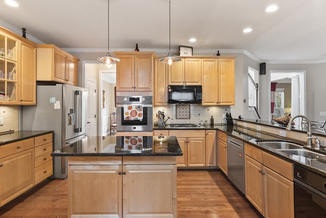 kitchen featuring appliances with stainless steel finishes, sink, light brown cabinets, a center island, and hanging light fixtures