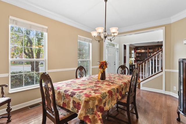 dining space with hardwood / wood-style floors, crown molding, and a chandelier