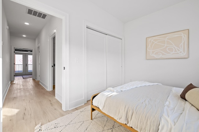 bedroom featuring french doors, light hardwood / wood-style floors, and a closet