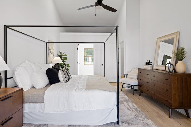 bedroom with light wood-type flooring, high vaulted ceiling, and ceiling fan