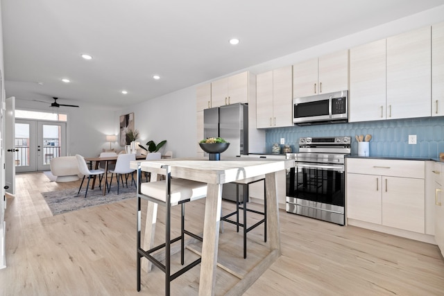 kitchen with ceiling fan, french doors, stainless steel appliances, light hardwood / wood-style flooring, and decorative backsplash