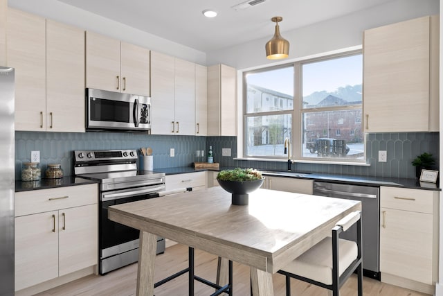 kitchen with backsplash, sink, stainless steel appliances, and light wood-type flooring