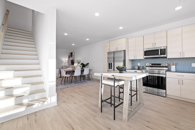 kitchen with backsplash, stainless steel appliances, and light hardwood / wood-style flooring