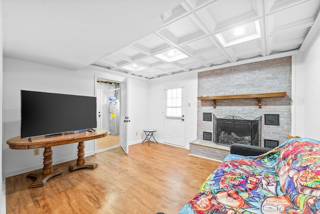 living room featuring coffered ceiling, light hardwood / wood-style floors, beamed ceiling, and a brick fireplace