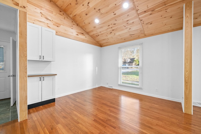 empty room with vaulted ceiling, wooden ceiling, and light hardwood / wood-style flooring