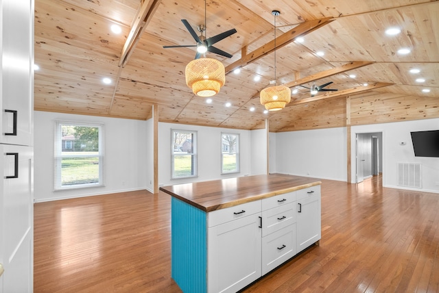 kitchen featuring light hardwood / wood-style floors, a healthy amount of sunlight, lofted ceiling with beams, butcher block countertops, and hanging light fixtures