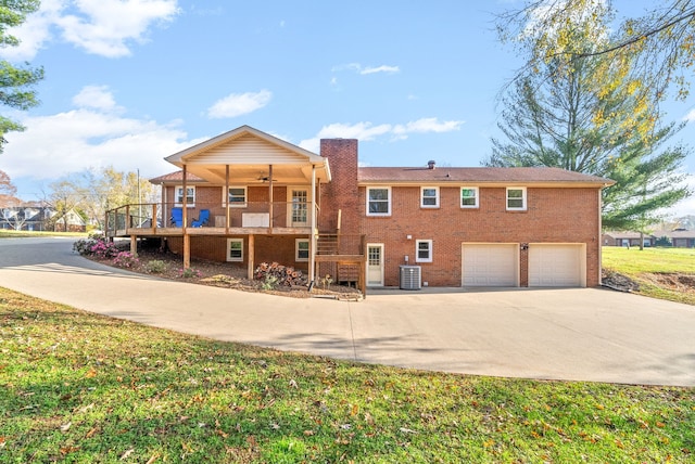 back of property featuring a lawn, ceiling fan, central air condition unit, a wooden deck, and a garage