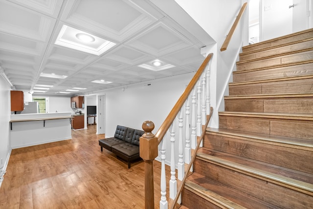 stairway featuring hardwood / wood-style flooring, ornamental molding, and coffered ceiling