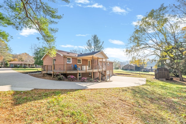 back of house featuring a lawn, a storage unit, and a deck