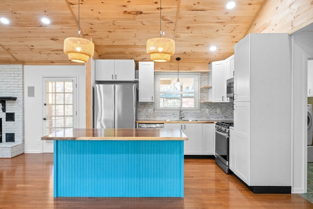 kitchen with a wealth of natural light, stainless steel appliances, pendant lighting, a center island, and white cabinetry