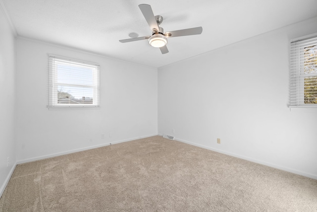 carpeted spare room featuring a wealth of natural light, ornamental molding, and ceiling fan