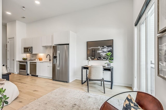 kitchen featuring white cabinets, sink, appliances with stainless steel finishes, tasteful backsplash, and light hardwood / wood-style floors