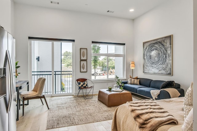 living room with light hardwood / wood-style flooring and a towering ceiling