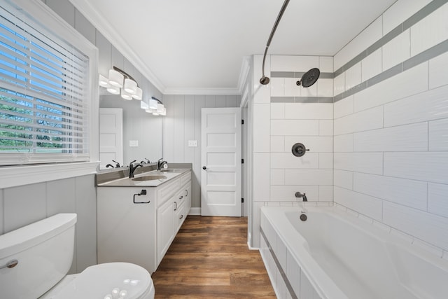 full bathroom with ornamental molding, hardwood / wood-style floors, toilet, vanity, and tiled shower / bath