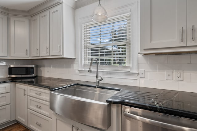 kitchen featuring backsplash, crown molding, sink, hanging light fixtures, and stainless steel appliances