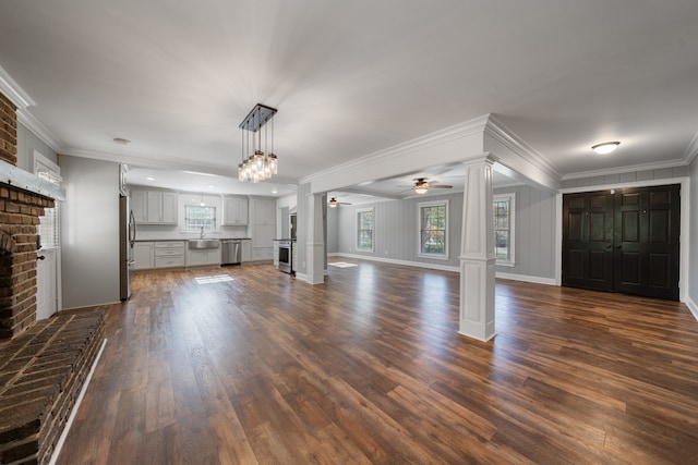 unfurnished living room featuring ornate columns, ornamental molding, ceiling fan, a fireplace, and dark hardwood / wood-style floors