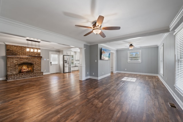 unfurnished living room with ceiling fan, dark hardwood / wood-style flooring, ornamental molding, and a brick fireplace