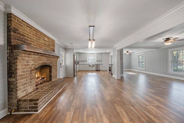 unfurnished living room with dark hardwood / wood-style floors, ceiling fan, ornamental molding, and a fireplace