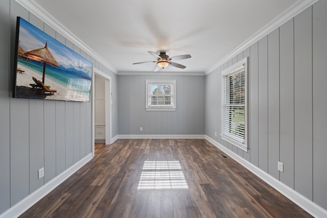 unfurnished room featuring wooden walls, dark hardwood / wood-style floors, ceiling fan, and ornamental molding