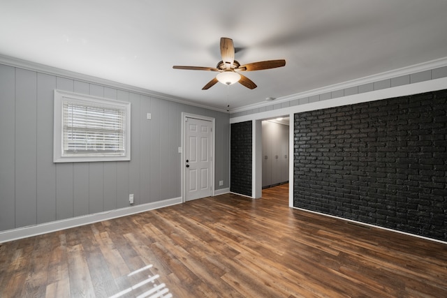 spare room with ceiling fan, dark hardwood / wood-style flooring, ornamental molding, and brick wall