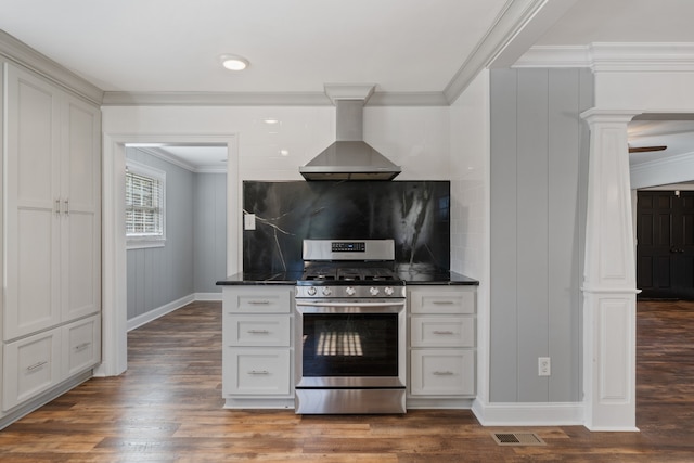 kitchen with decorative backsplash, dark stone counters, dark wood-type flooring, wall chimney range hood, and stainless steel range with gas cooktop