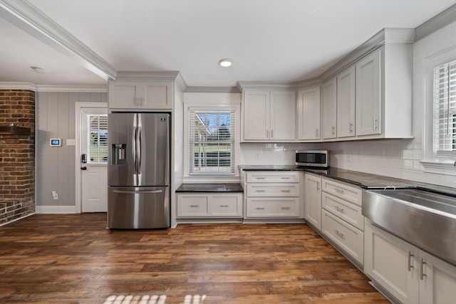 kitchen with a wealth of natural light, stainless steel appliances, dark hardwood / wood-style floors, and ornamental molding