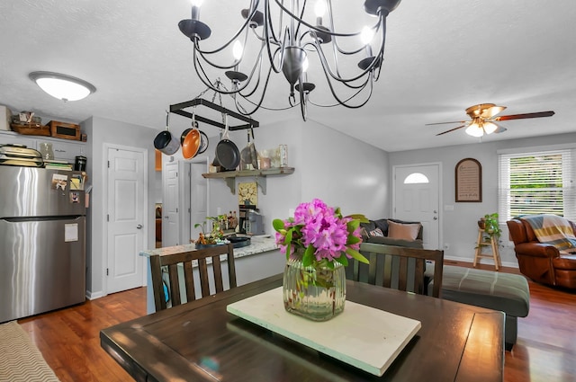 dining space with a textured ceiling, dark hardwood / wood-style floors, and ceiling fan with notable chandelier