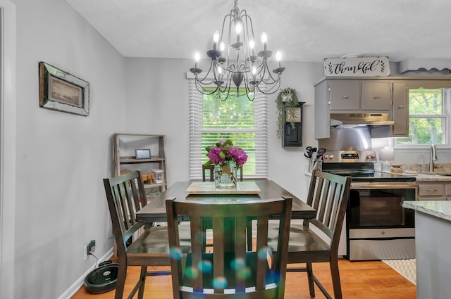 dining room featuring light hardwood / wood-style flooring, sink, a textured ceiling, and a chandelier