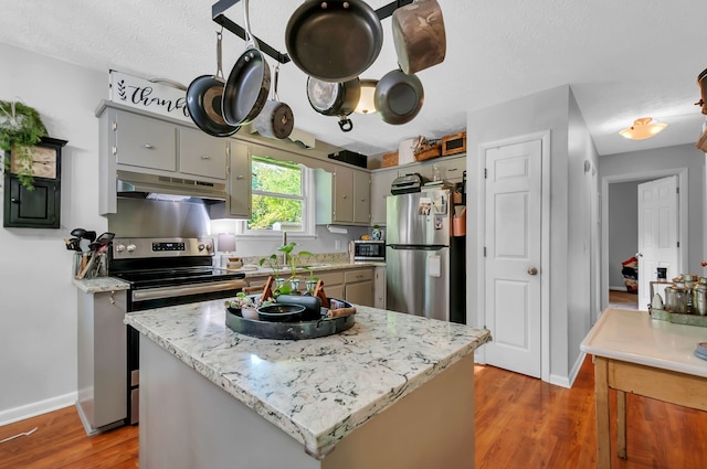 kitchen featuring gray cabinets, a kitchen island, stainless steel appliances, and dark wood-type flooring