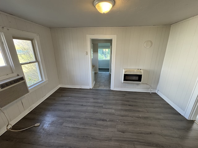 unfurnished living room featuring dark wood-type flooring, wooden walls, and heating unit