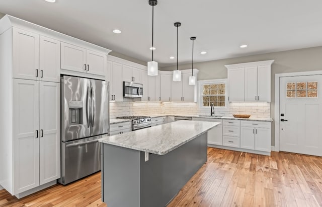 kitchen featuring white cabinetry, a kitchen island, stainless steel appliances, and light hardwood / wood-style floors