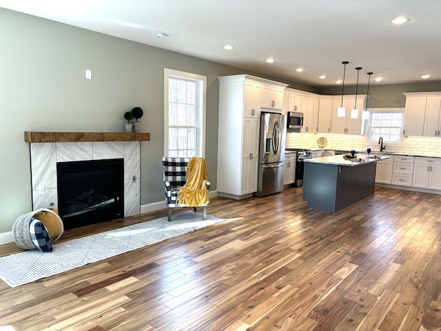 kitchen featuring decorative light fixtures, a kitchen island, a healthy amount of sunlight, and appliances with stainless steel finishes