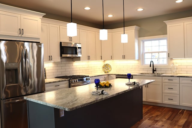 kitchen featuring appliances with stainless steel finishes, decorative light fixtures, dark hardwood / wood-style floors, and sink