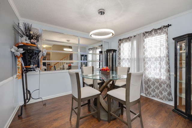 dining room with dark hardwood / wood-style flooring, ornamental molding, and a textured ceiling