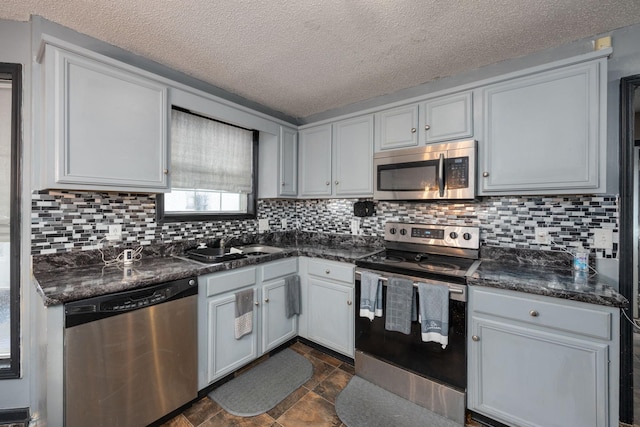 kitchen with appliances with stainless steel finishes, a textured ceiling, tasteful backsplash, and white cabinetry