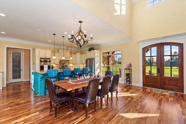 dining room featuring crown molding, french doors, a chandelier, and light wood-type flooring