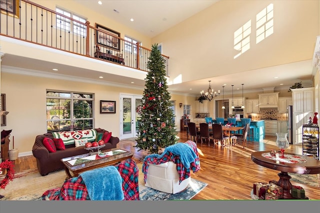 living room featuring a chandelier, crown molding, a towering ceiling, and light hardwood / wood-style floors