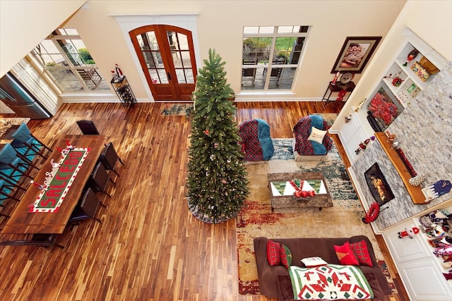 living room featuring a stone fireplace, hardwood / wood-style floors, and french doors